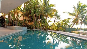 A swimming pool with clear water, surrounded by palm trees and a tiled deck. - Seaside Sanctuary 5 bed, 5 bath pool home (Tavernier)