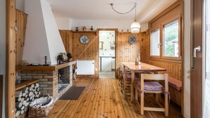A wooden interior with a kitchen area, a dining table with chairs, and a fireplace.