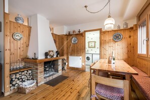 A cozy wooden interior with a fireplace, a dining table, and a bench.