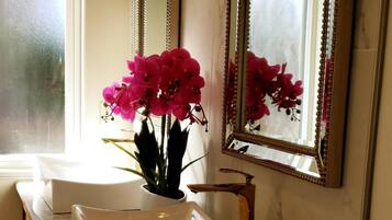 Ein Badezimmer mit zwei Waschbecken, einem großen Spiegel und einer Vase mit rosa Blumen.
