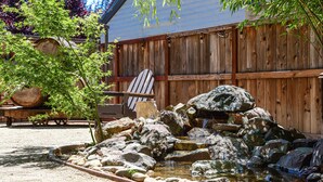 A garden with a pond, rocks, and a wooden fence. - Charm and Comfort in Quiet Lodi Neighborhood (Lodi)