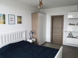 A bedroom with a bed, bedside table, lamp, wardrobe, and a door.