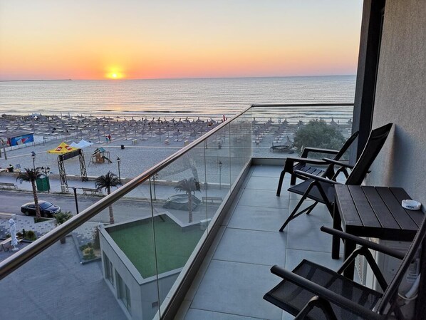 A balcony with a view of the sunset over the sea, a pool, and beach umbrellas. - 3 rooms beachfront propriety with amazing panorama views (Mamaia-Sat)
