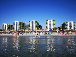 A beachfront hotel with multiple high-rise buildings, beach umbrellas, and people enjoying the water. - 3 rooms beachfront propriety with amazing panorama views (Mamaia-Sat)