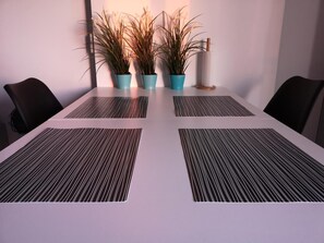 A conference table with four chairs, three potted plants, and a white cylindrical object on the table.