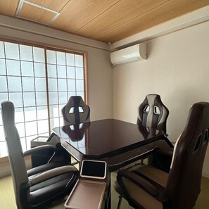 Una sala de conferencias con una mesa de vidrio, cuatro sillas, una computadora portátil y una ventana con persianas.