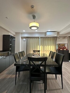 A modern dining area with a long table, black chairs, and a pendant light.