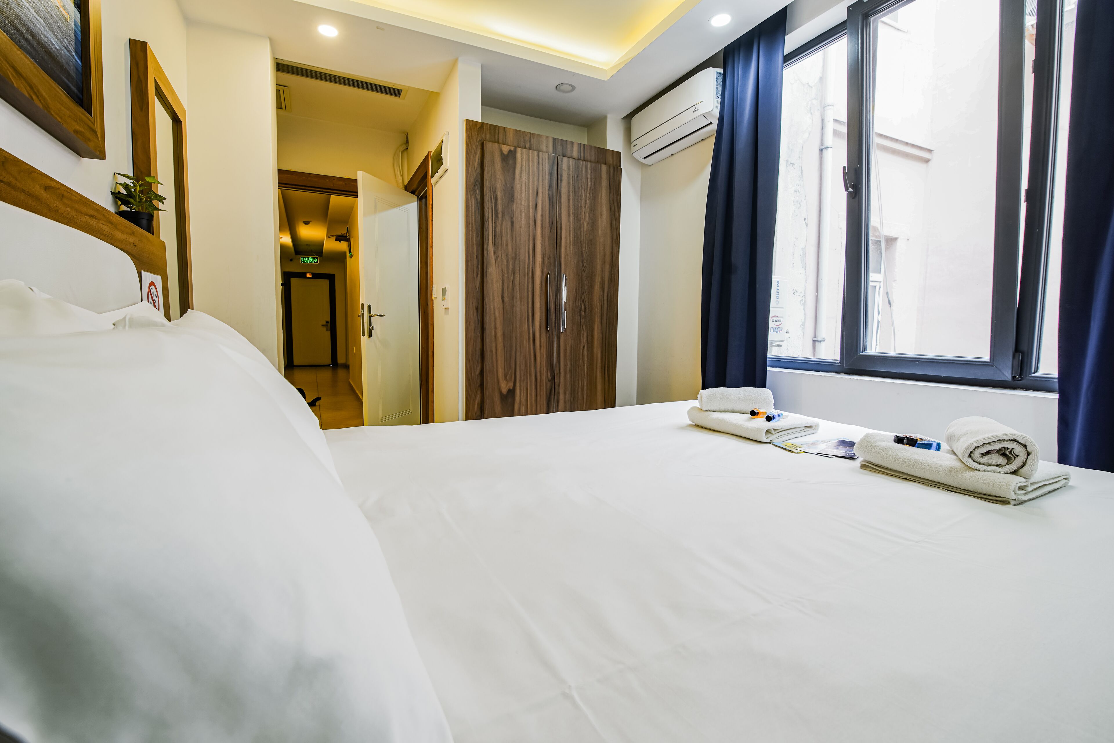 Une chambre d’hôtel avec un grand lit, une armoire en bois et une fenêtre avec des rideaux.