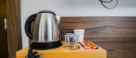 Un plateau en bois avec une bouilloire, un verre, une tasse et un paquet de collations, le tout posé sur une table.