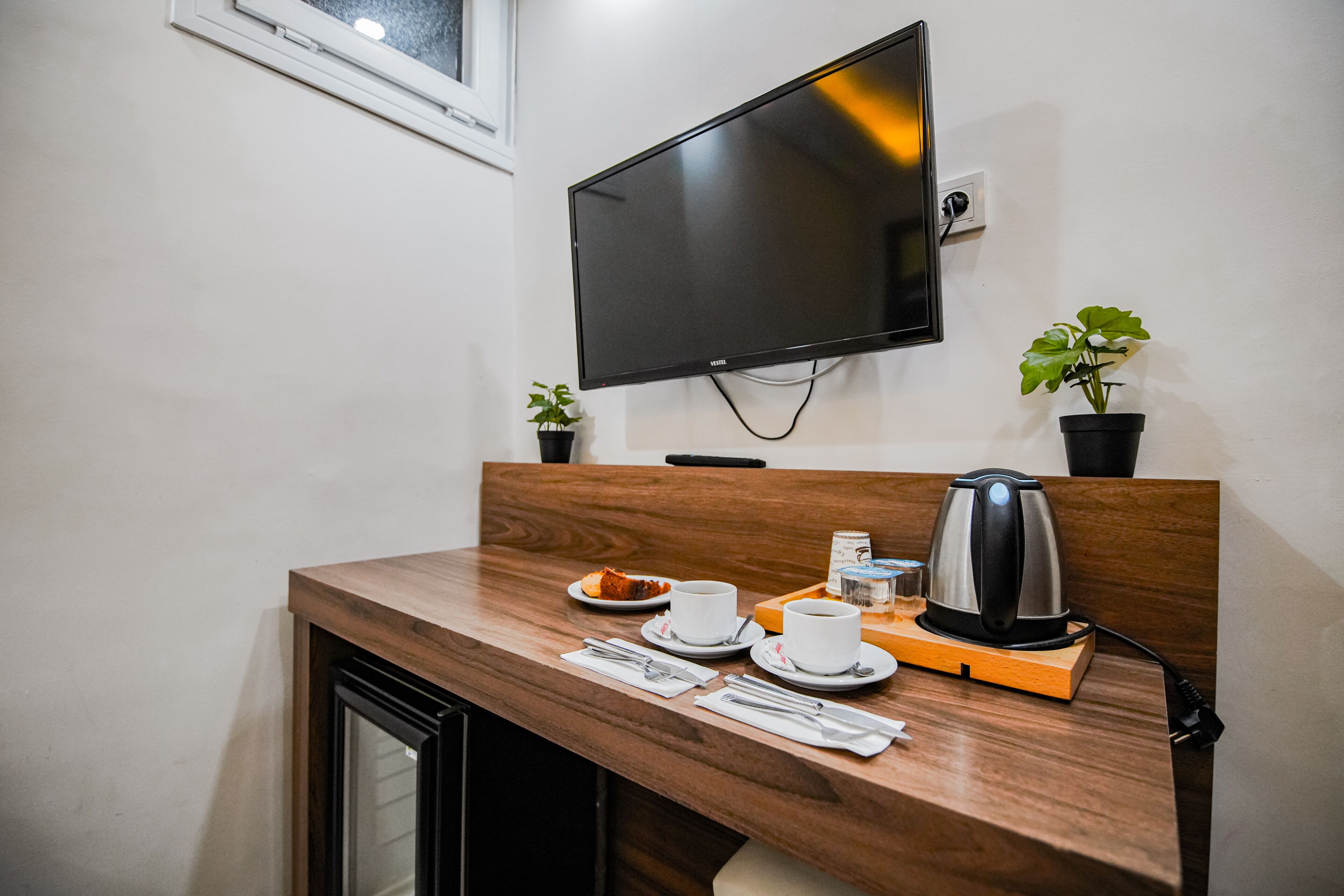 Une table de petit-déjeuner bien mise, avec une bouilloire, des tasses et une petite plante.