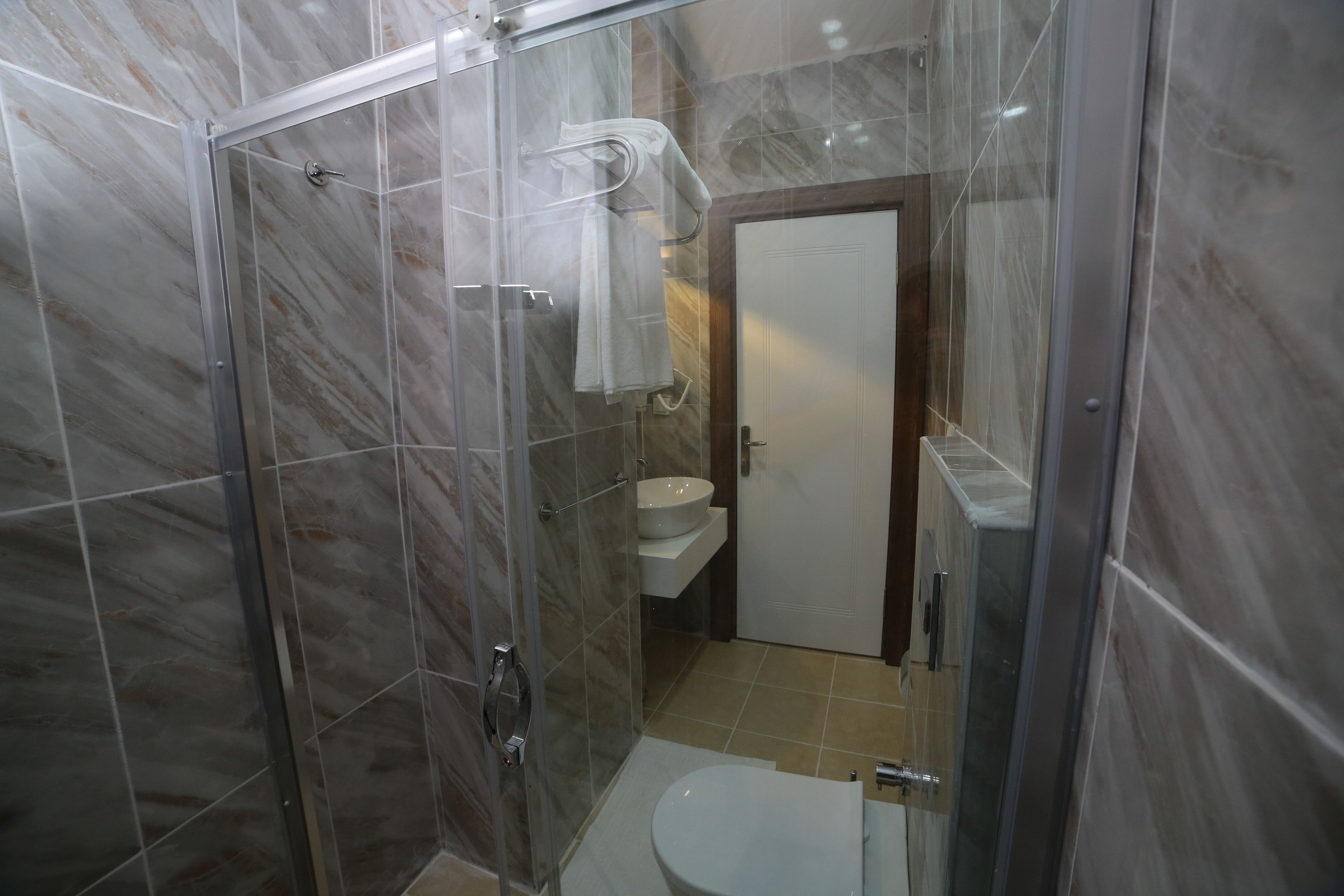 Un baño con ducha acristalada, inodoro blanco y lavabo de porcelana blanca.