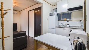 Une cuisine compacte équipée d’un réfrigérateur, d’un four à micro-ondes et d’une bouilloire posée sur le plan de travail.