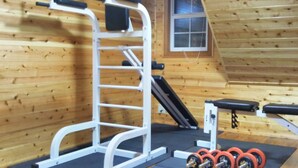 Une salle de sport équipée d’une barre de traction, d’un banc et d’haltères rouges.