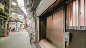 A narrow street with a bicycle parked by a building with a metal gate. - Tsuruhashi Guest House (Osaka)
