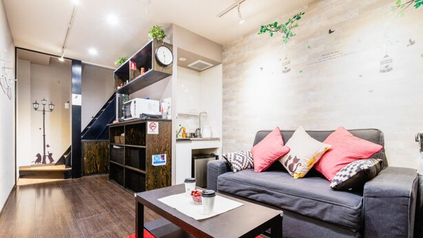 A modern living room with a grey sofa, red rug, and a coffee table. - Tsuruhashi Guest House (Osaka)