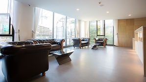 Amplia sala de estar con sofás de cuero, una mesa de centro de vidrio y grandes ventanales con vistas a la ciudad.