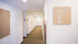 Pasillo de hotel con puertas de madera, placas de números de habitaciones y pisos alfombrados.