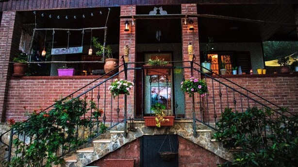 A brick building with a staircase leading to a door, potted plants, and hanging lights. - Oasi LIV Palermo (Piana degli Albanesi)