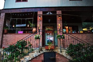 A brick building with a staircase leading to a door, potted plants, and hanging lights. - Oasi LIV Palermo (Piana degli Albanesi)