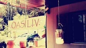 A wooden porch with hanging lights and potted plants. A sign with the text "OASILIV" is visible. - Oasi LIV Palermo (Piana degli Albanesi)