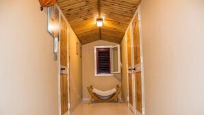 A narrow hallway with wooden doors, a hammock, and a small window with shutters. - Oasi LIV Palermo (Piana degli Albanesi)