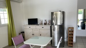 A compact kitchen with a foldable table and chairs, a refrigerator, and a window with curtains. - Villa Bougainvilliers with private pool in Le Diamant (le diamant)