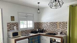 A compact kitchen with a washing machine, microwave, stove, and a small oven. - Villa Bougainvilliers with private pool in Le Diamant (le diamant)