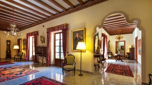 Un hall espacioso con techos altos, candelabros ornamentales y alfombras estampadas.