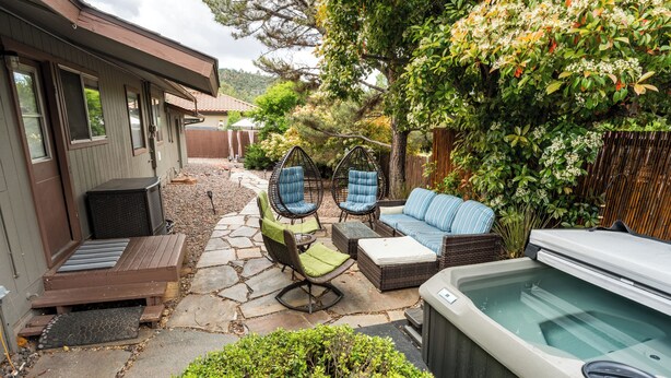 Een terras met een hottub, rieten stoelen en een bank.