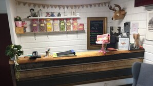 A rustic counter with jars of sweets, a chalkboard menu, and a deer head decoration.