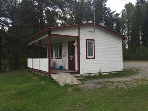 Una cabana petita d'una sola planta amb un porxo, una porta i una finestra.