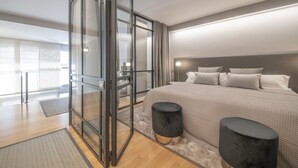 Un dormitorio moderno con una cama grande, un separador de vidrio y vistas al exterior.