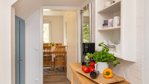 Une cuisine avec une table en bois, une machine à café et des légumes frais.