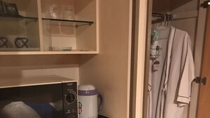Una kitchenette compacta con microondas, cafetera y un refrigerador pequeño.