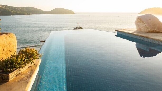 An infinity pool with a clear view of the sea and distant hills. - Steps from the beach, far from routine. An experience beyond the ordinary (Playa la ropa)