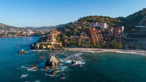 A coastal town with buildings on a hillside overlooking the sea. - Steps from the beach, far from routine. An experience beyond the ordinary (Playa la ropa)