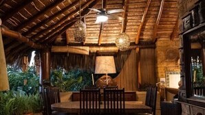 A rustic dining area with a high wooden ceiling, a round table with chairs, and a stone counter. - Steps from the beach, far from routine. An experience beyond the ordinary (Playa la ropa)