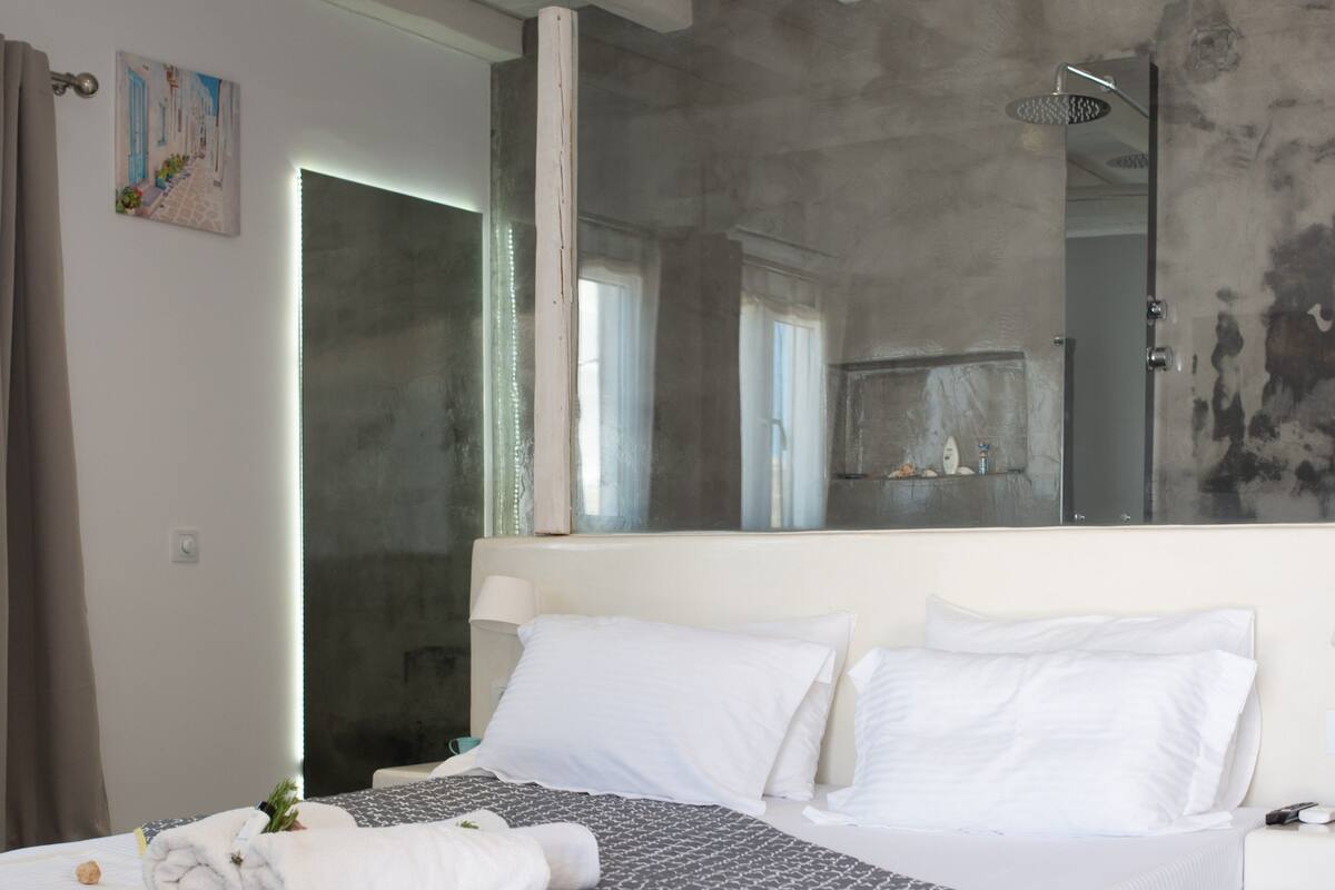 Een moderne hotelkamer met een groot bed, een douchegedeelte en uitzicht op de stad.