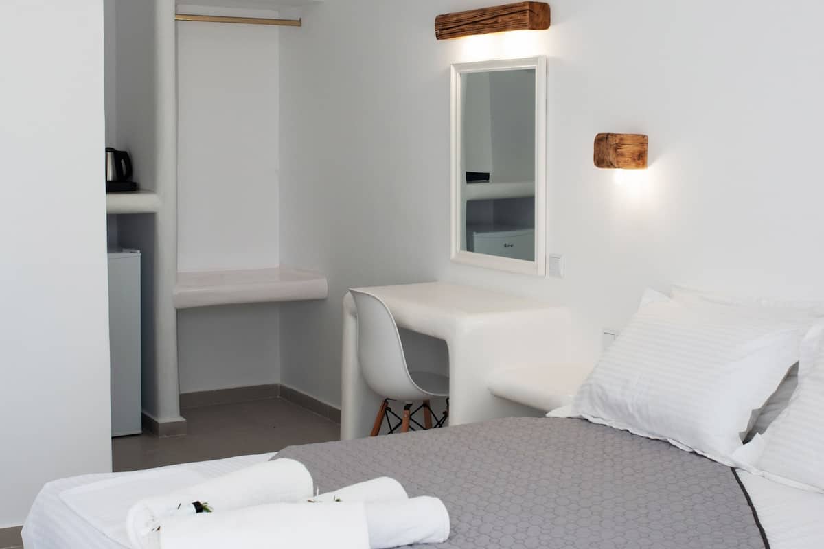 Een moderne hotelkamer met een opgemaakt bed, een klein bureau en een spiegel.