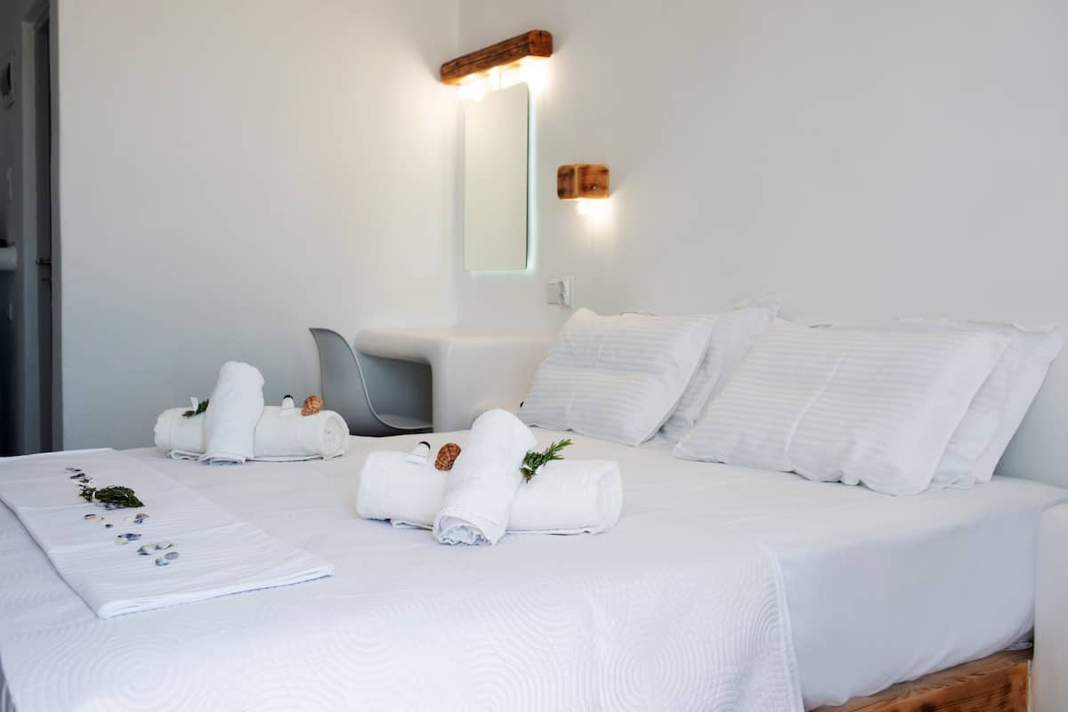 Een opgemaakt bed met witte lakens, een opgerolde handdoek en een decoratief object op het bed.
