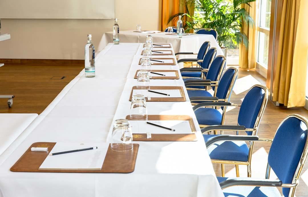 A conference room with a long table, chairs, water bottles, glasses, and notepads.