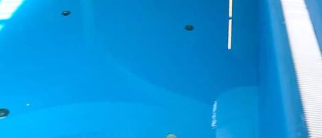 A blue swimming pool with a white edge and a drain in the center.