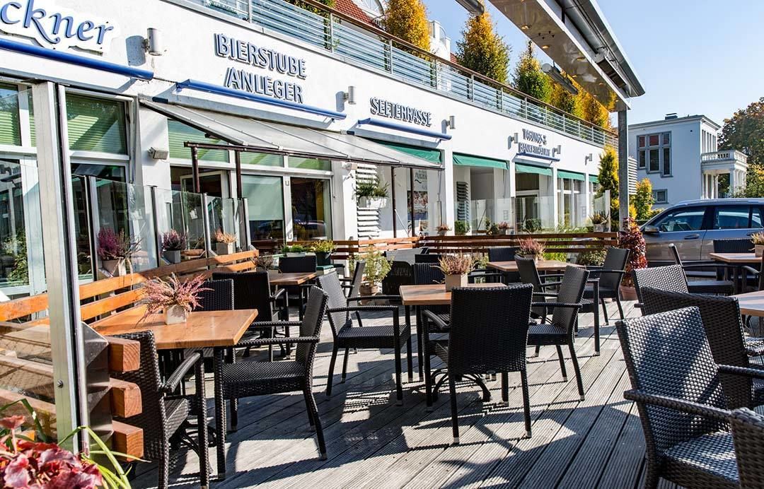 Un espace extérieur aménagé avec des tables et des chaises, une terrasse en bois et un bâtiment doté d’une enseigne.
