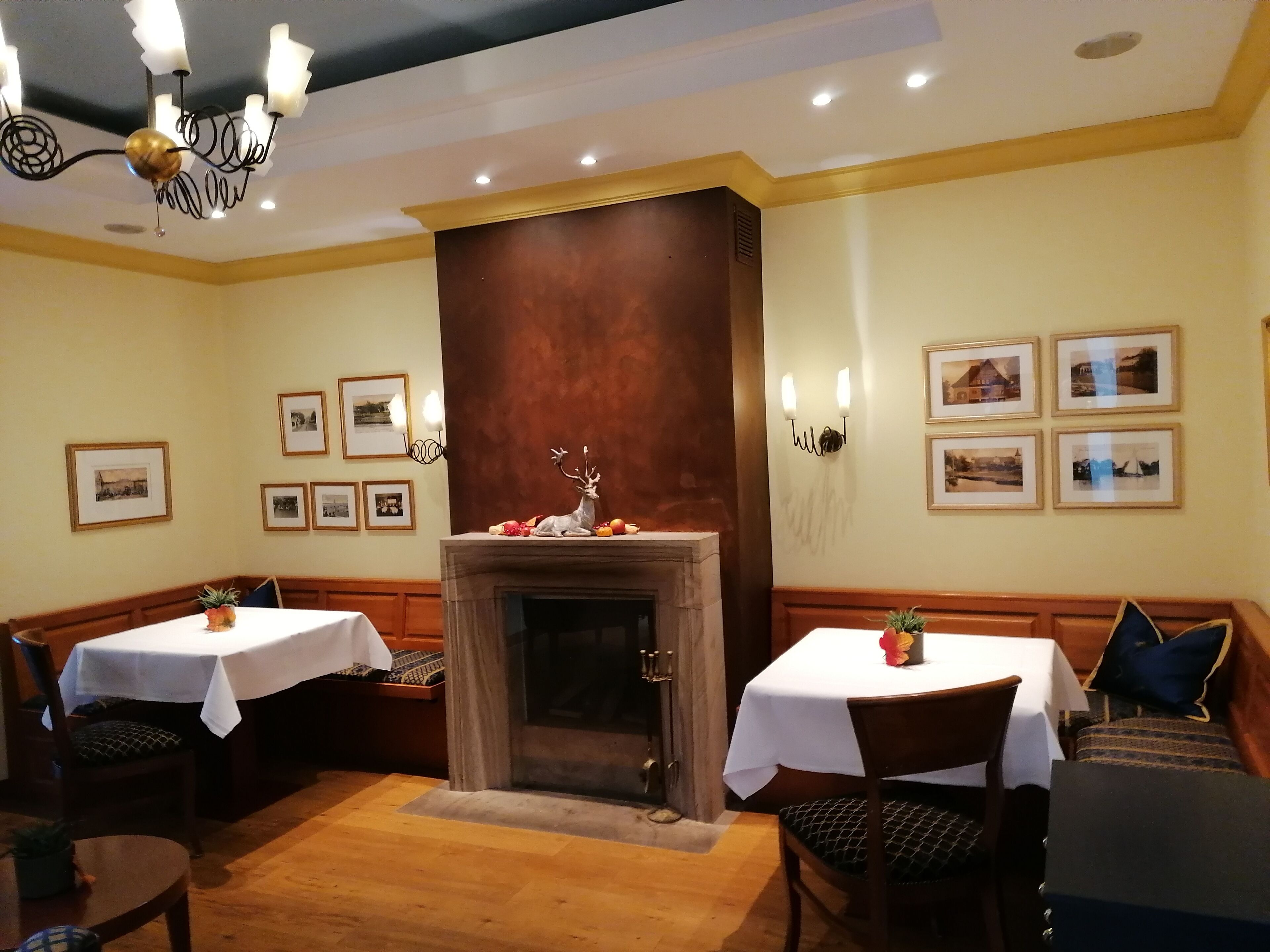 Un espace repas agrémenté d’une cheminée, de bancs en bois et de tables recouvertes de nappes blanches.