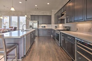 A modern kitchen with dark cabinets, stainless steel appliances, and a central island.
