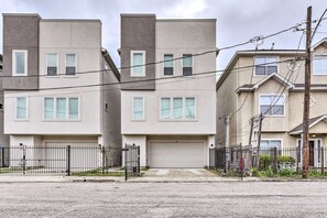 A modern two-story residential building with a flat roof, a garage, and a black metal fence. - Central Houston 3-bedroom, 3.5-bath vacation rental townhouse! (Houston)