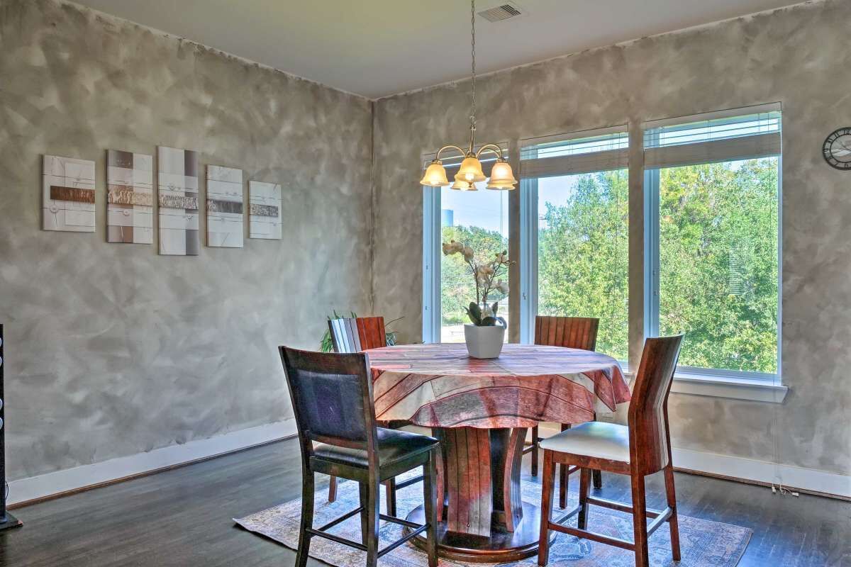 A dining area with a round table, chairs, a chandelier, and artwork on the wall.