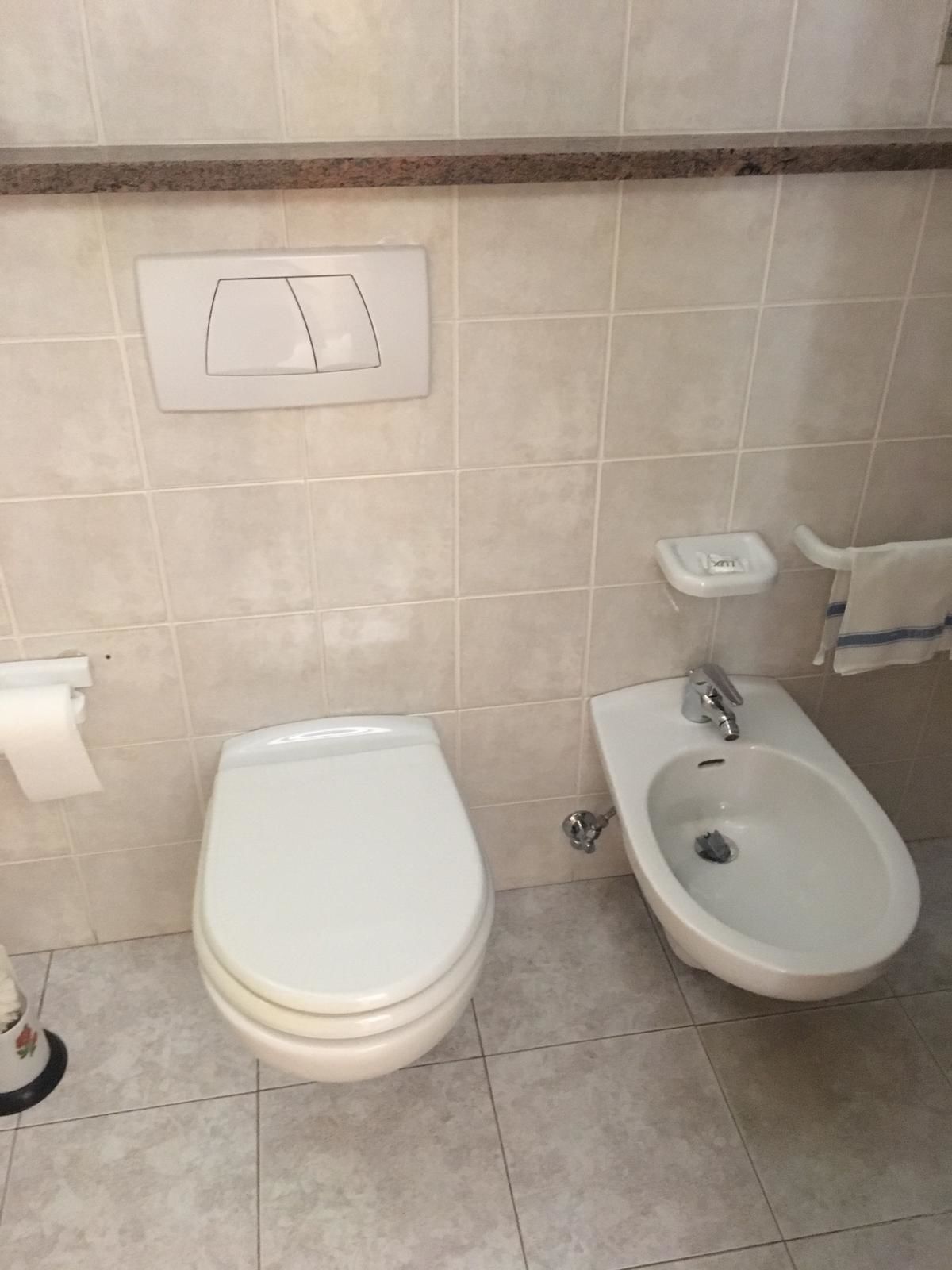 A bathroom with a toilet, bidet, and a towel rack.