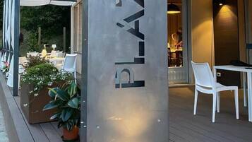 Un edificio moderno con un letrero que dice 'ABERGO SAR RISTORANTE PLAZA' y un área de estar al aire libre.