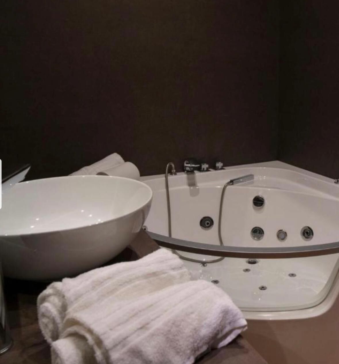 A bathroom with a white bathtub, a white sink, and a white towel on the counter.
